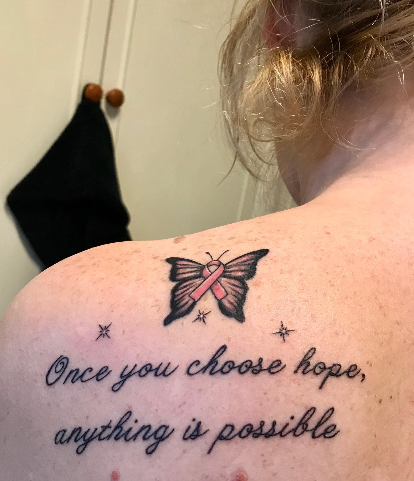 Tattoo of a butterfly with a pink ribbon and the text "Once you choose hope, anything is possible"